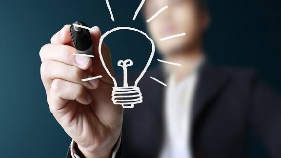 A person in suit in background is writing a bulb on the screen interface