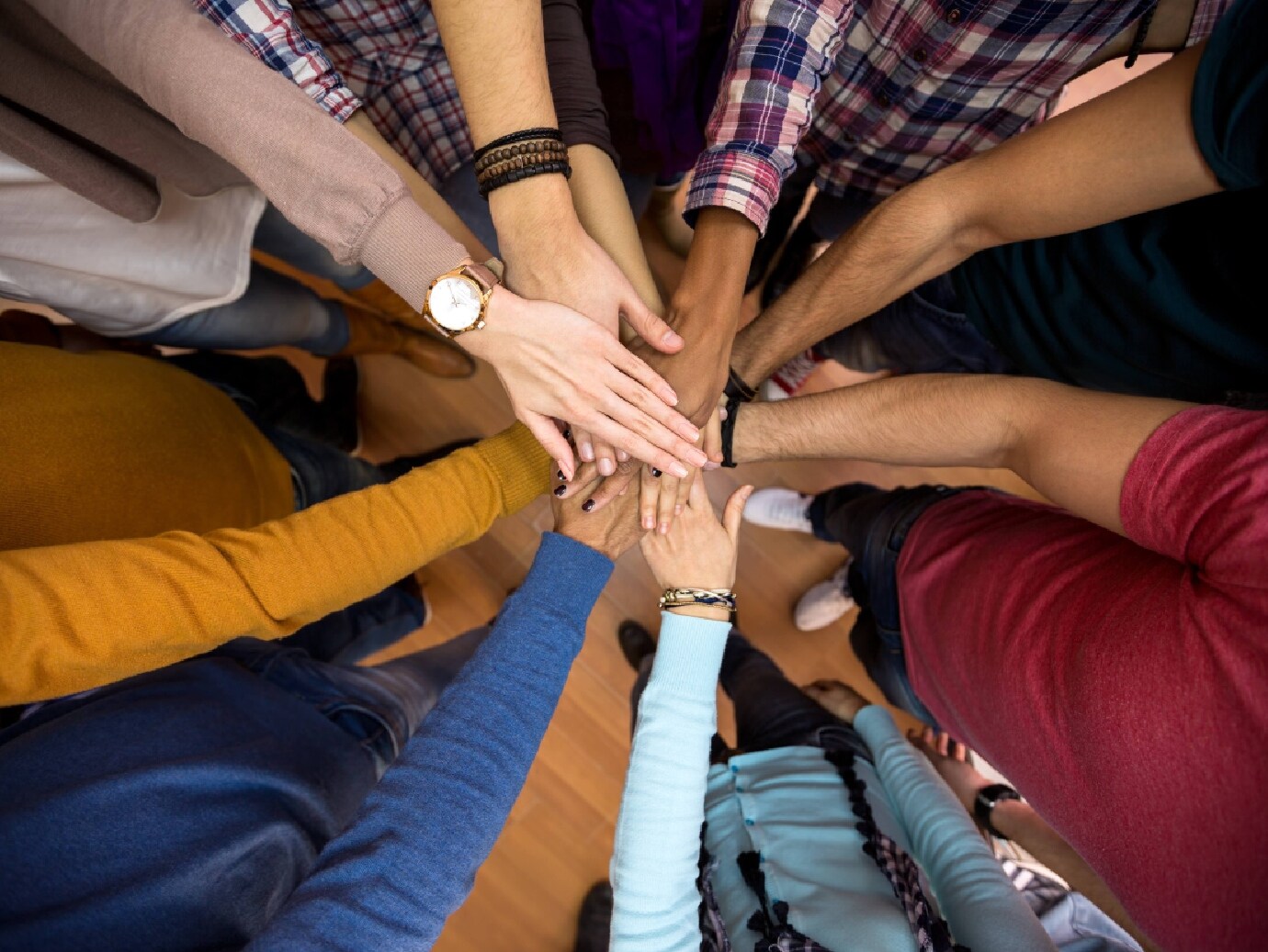 Close-up of hands of people placed on one another as in a huddle