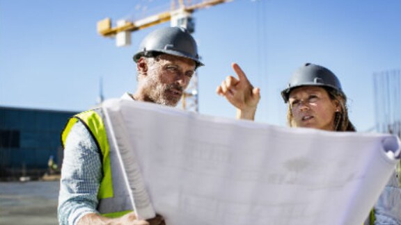 Two architects at work while holding the floor plan