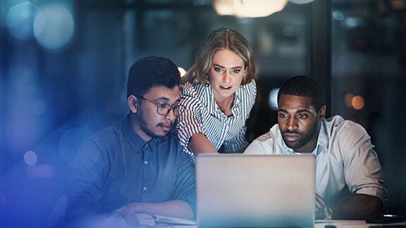 Three young professionals discussing work over a laptop